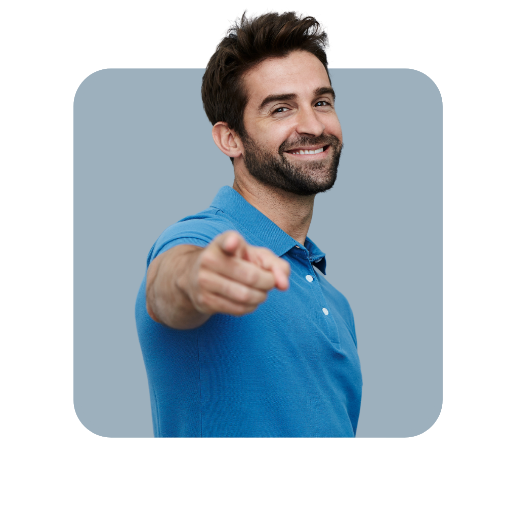 Homme tee shirt bleu qui sourit sur fond bleu gris pointant du doigt face à lui.